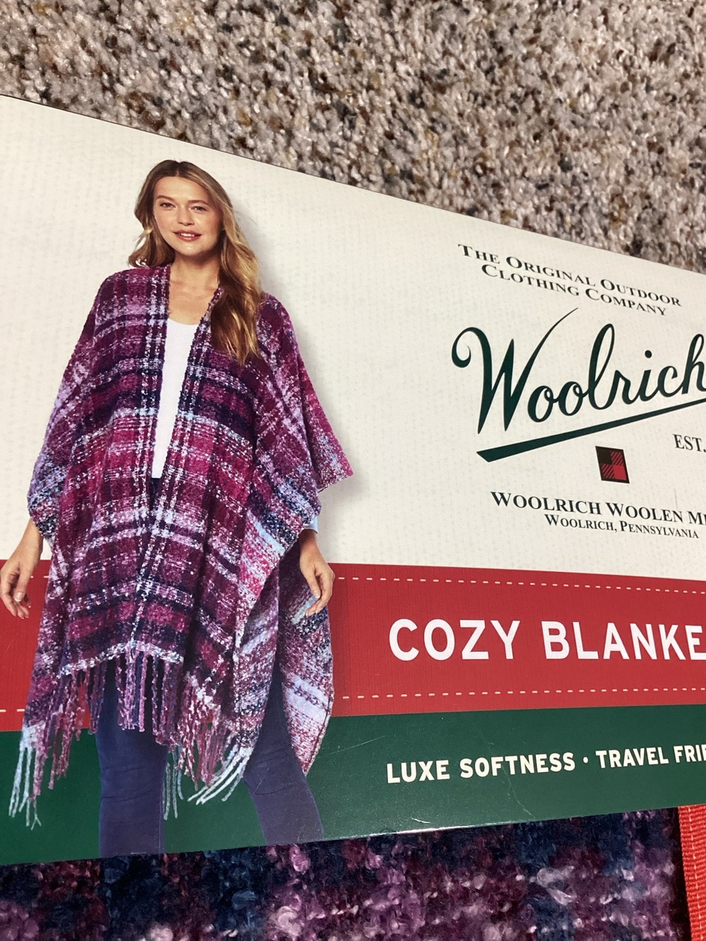 Cozy Woolrich blanket wrap with plaid design. Features fringe trim